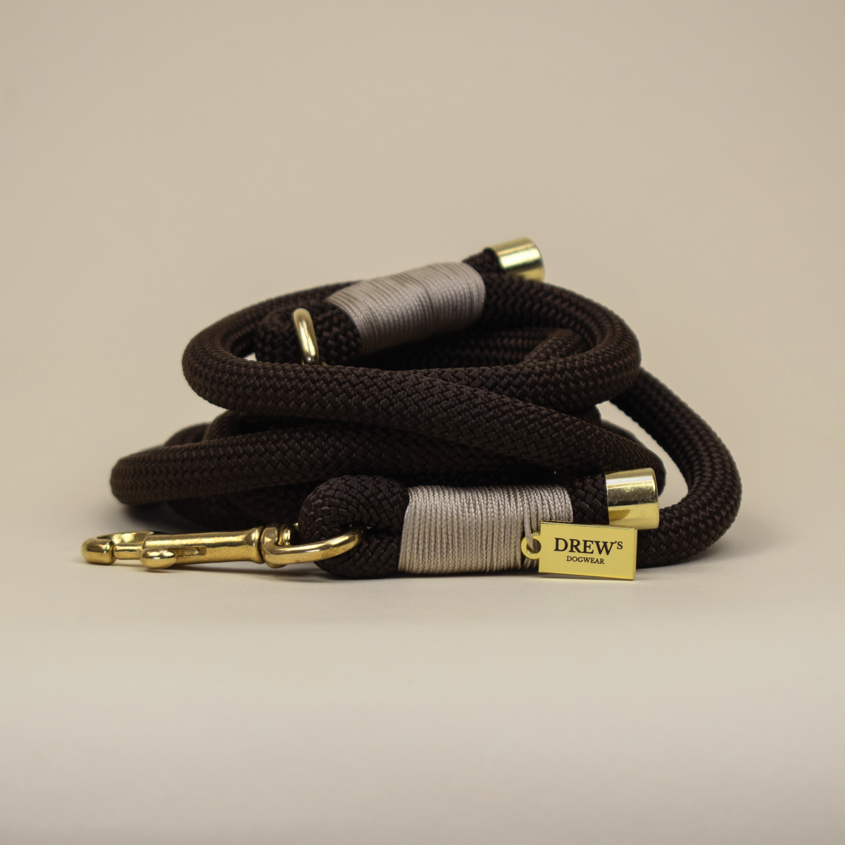 Dog leash with gold ends and 'Drew's' label on a beige background