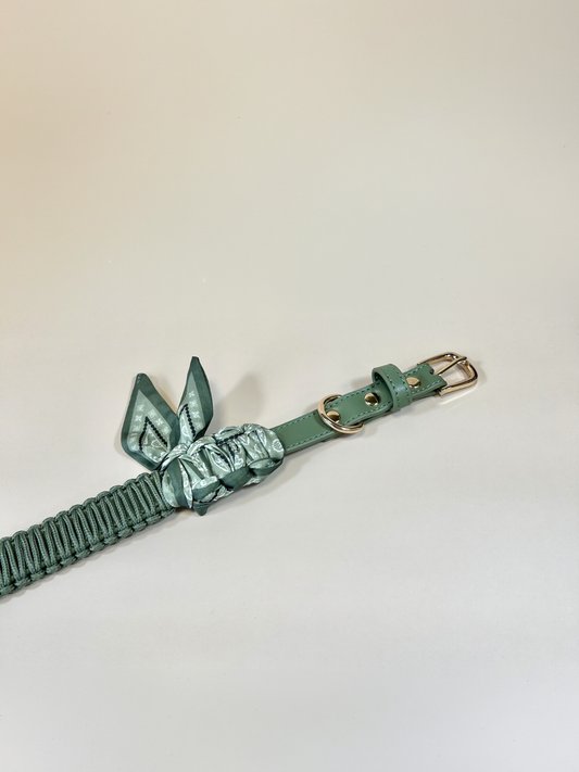 Green leather belt with bow detail on a light gray background