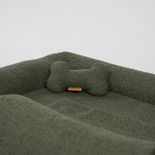 Green pet bed with a bone-shaped pillow on a light gray background