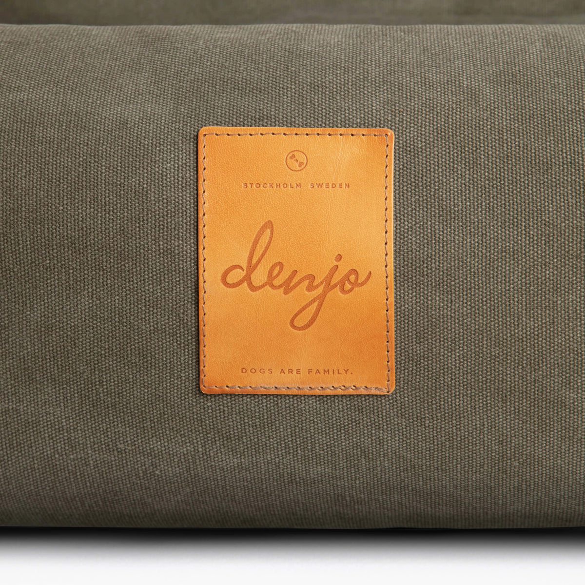 Gray cushion with a brown leather label featuring the brand 'denjo'.