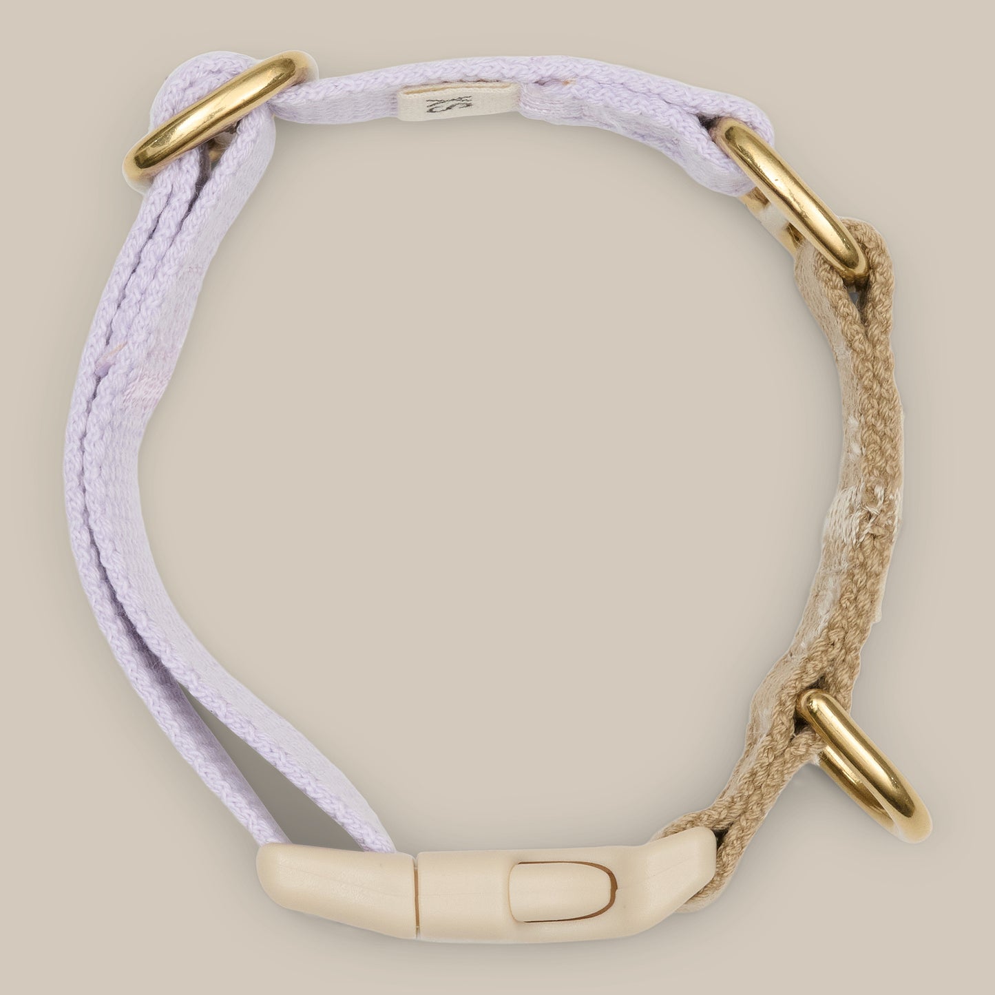 Bracelet with gold clasps and purple and beige straps on a beige background