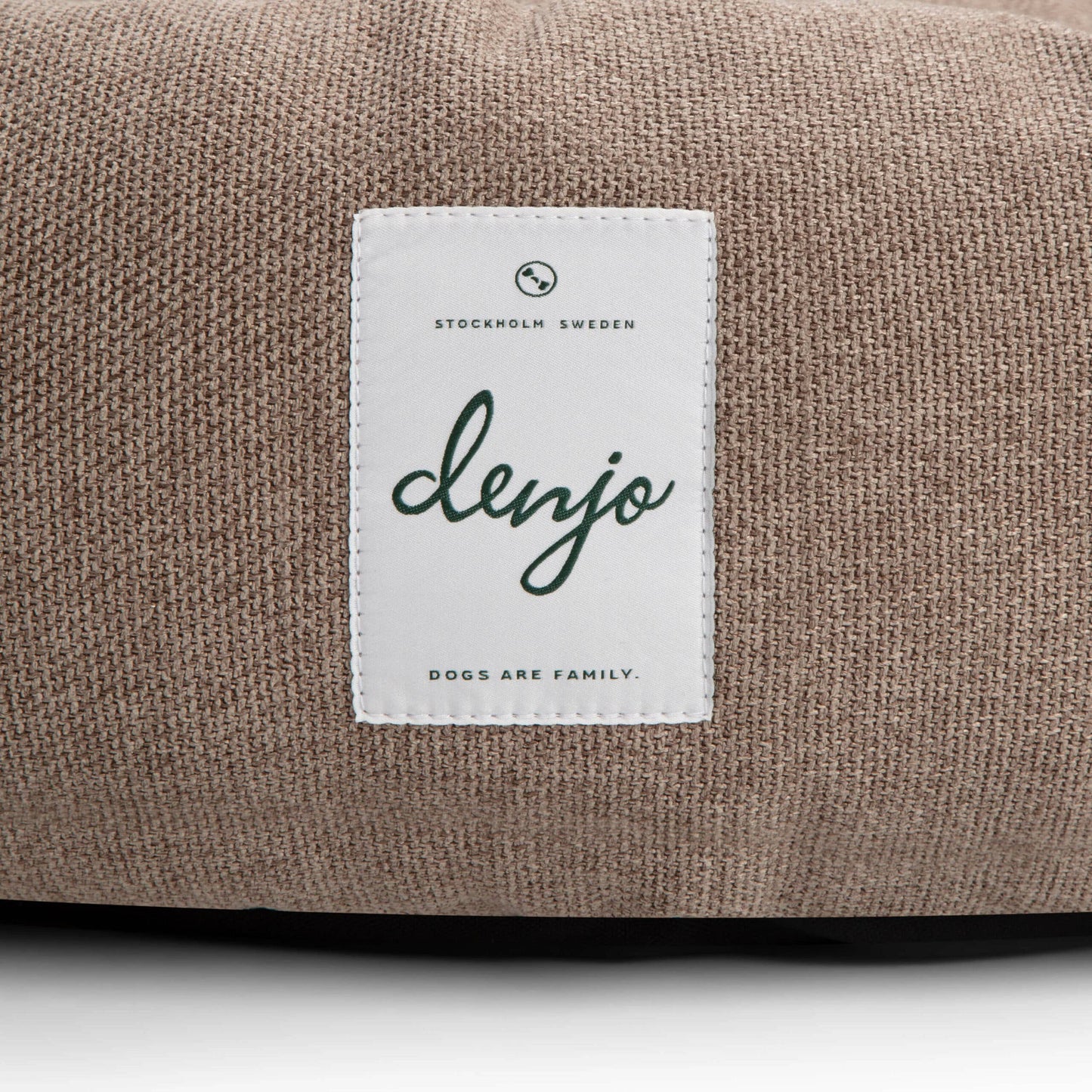 Brown fabric surface with a white label featuring the brand 'denjo'.