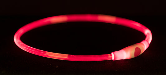 Pink and red striped glowing bracelet on a black background