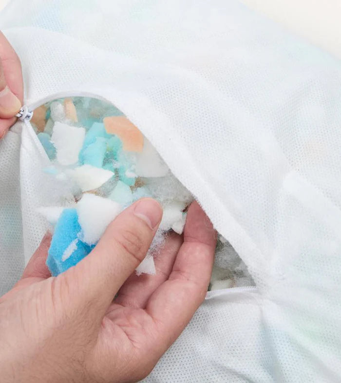 Close-up of a hand zipping a colorful fabric item, possibly a dog bed.