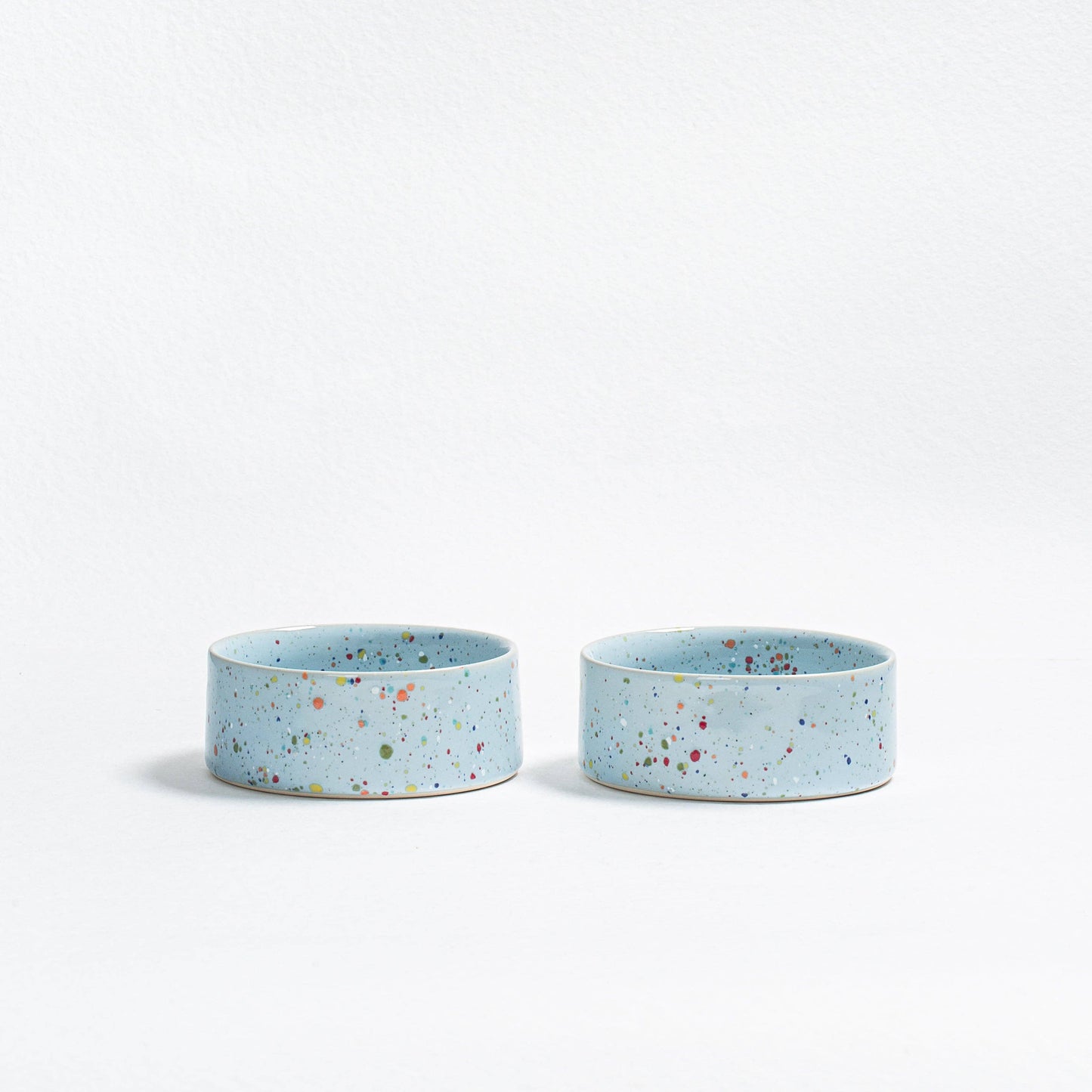 Two small blue ceramic bowls with speckled pattern on a white background