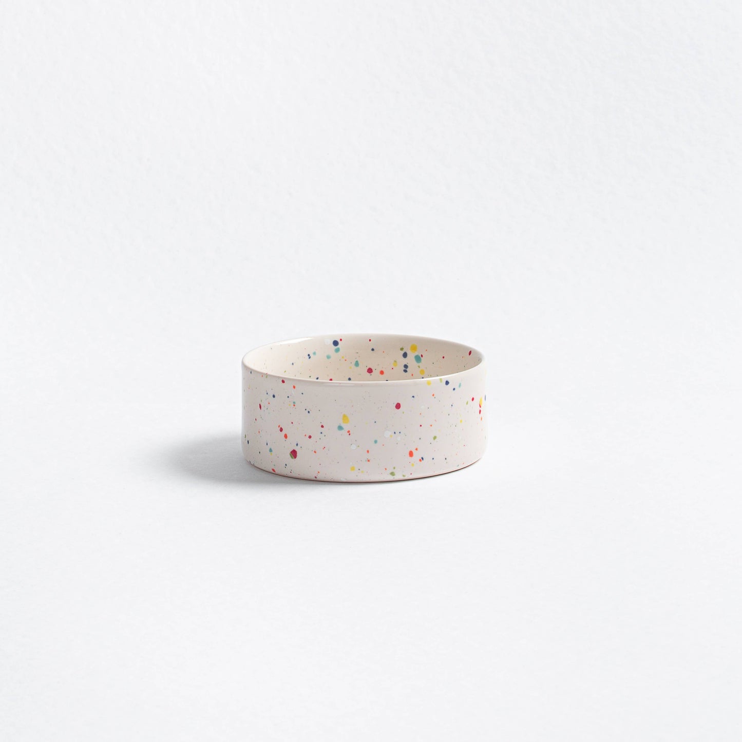 White ceramic bowl with colorful speckles on a light gray background