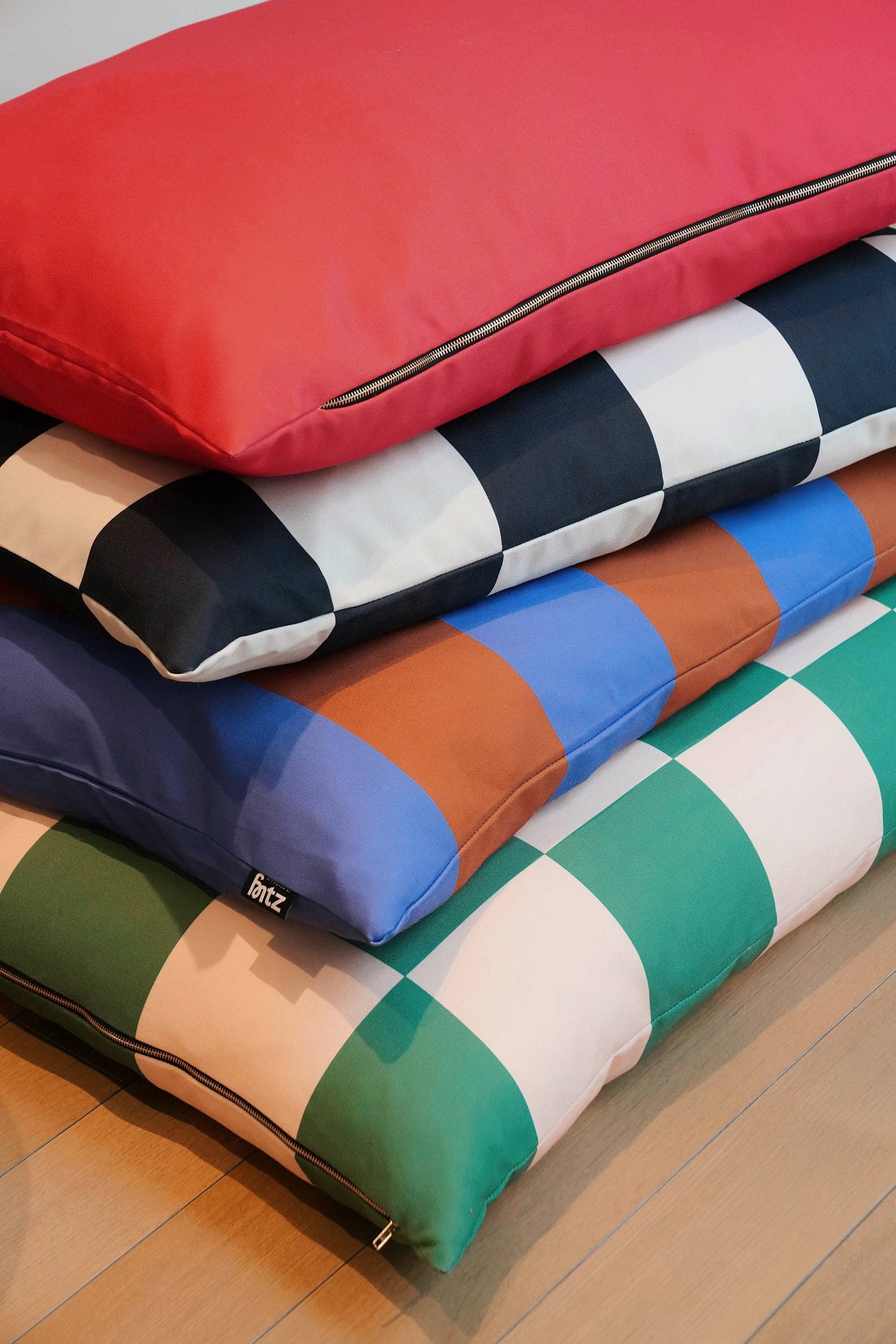 Stack of colorful checkered pillows on a wooden floor