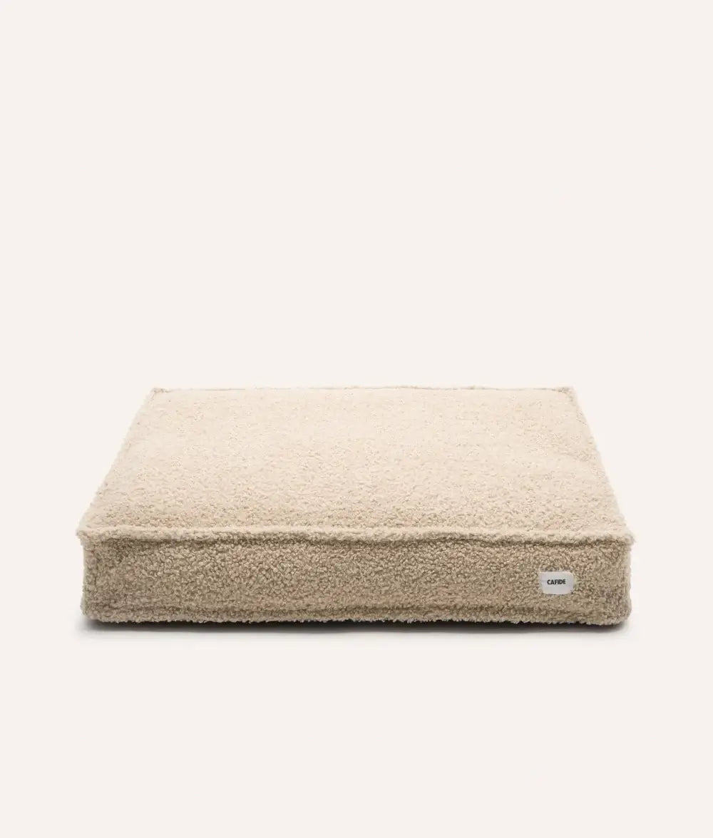 Beige pet bed with a visible brand label on a white background