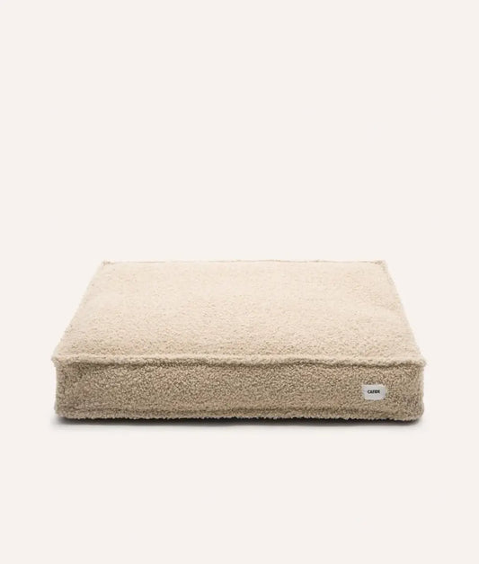 Beige pet bed with a visible brand label on a white background