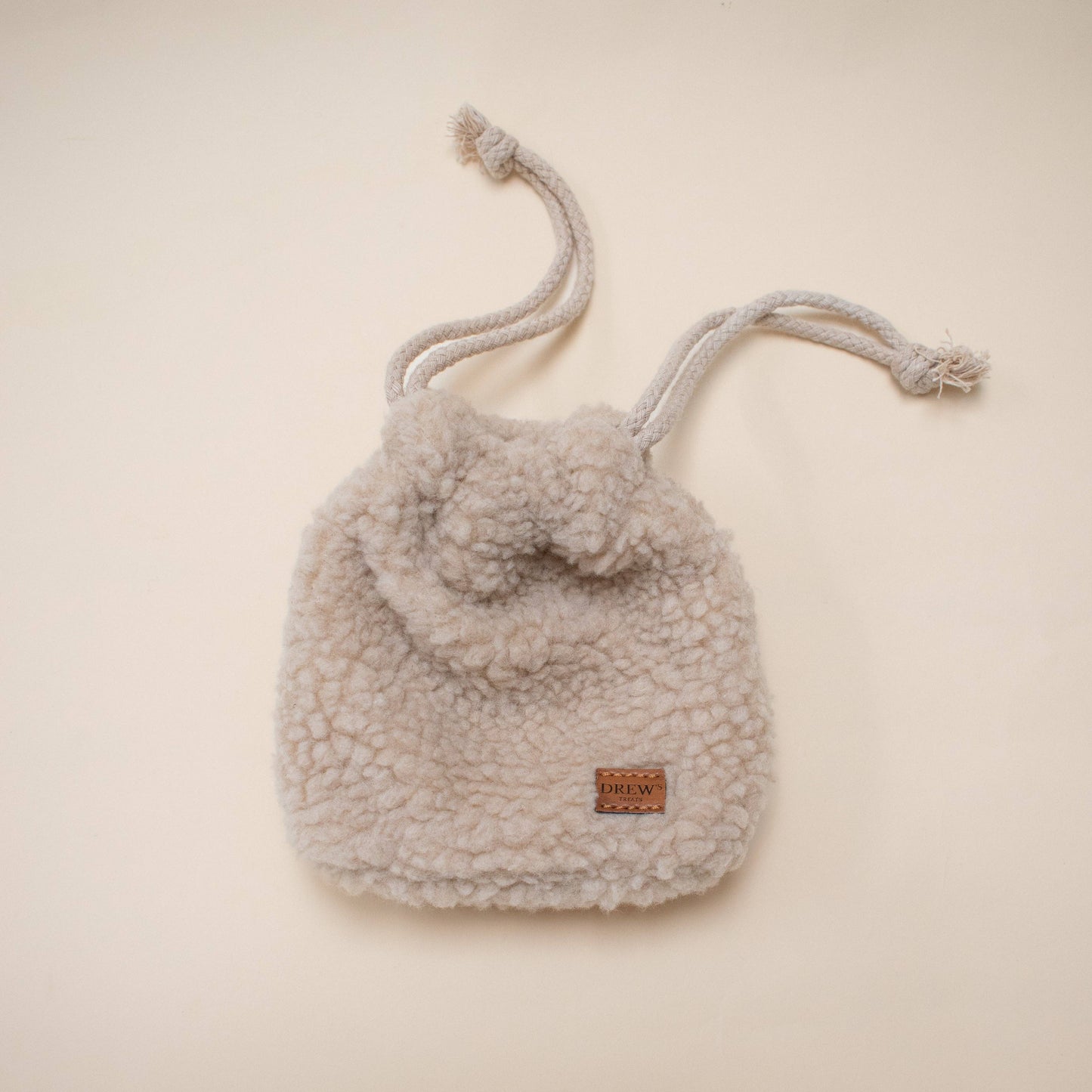 Shearling drawstring bag with pom-pom on a beige background