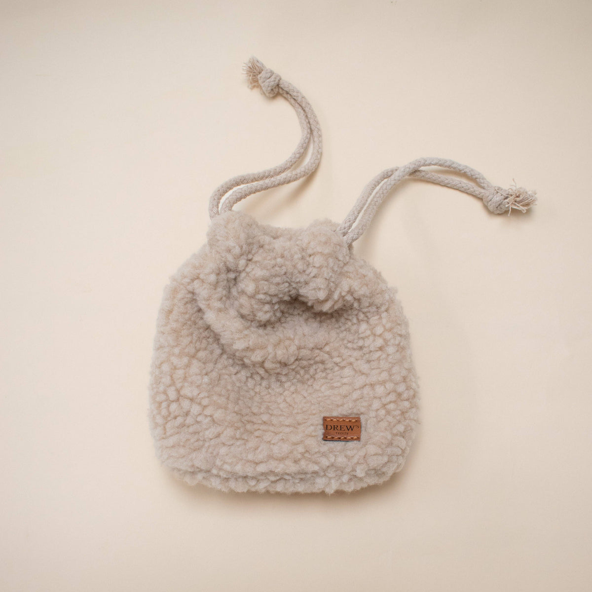 Shearling drawstring bag with pom-pom on a beige background