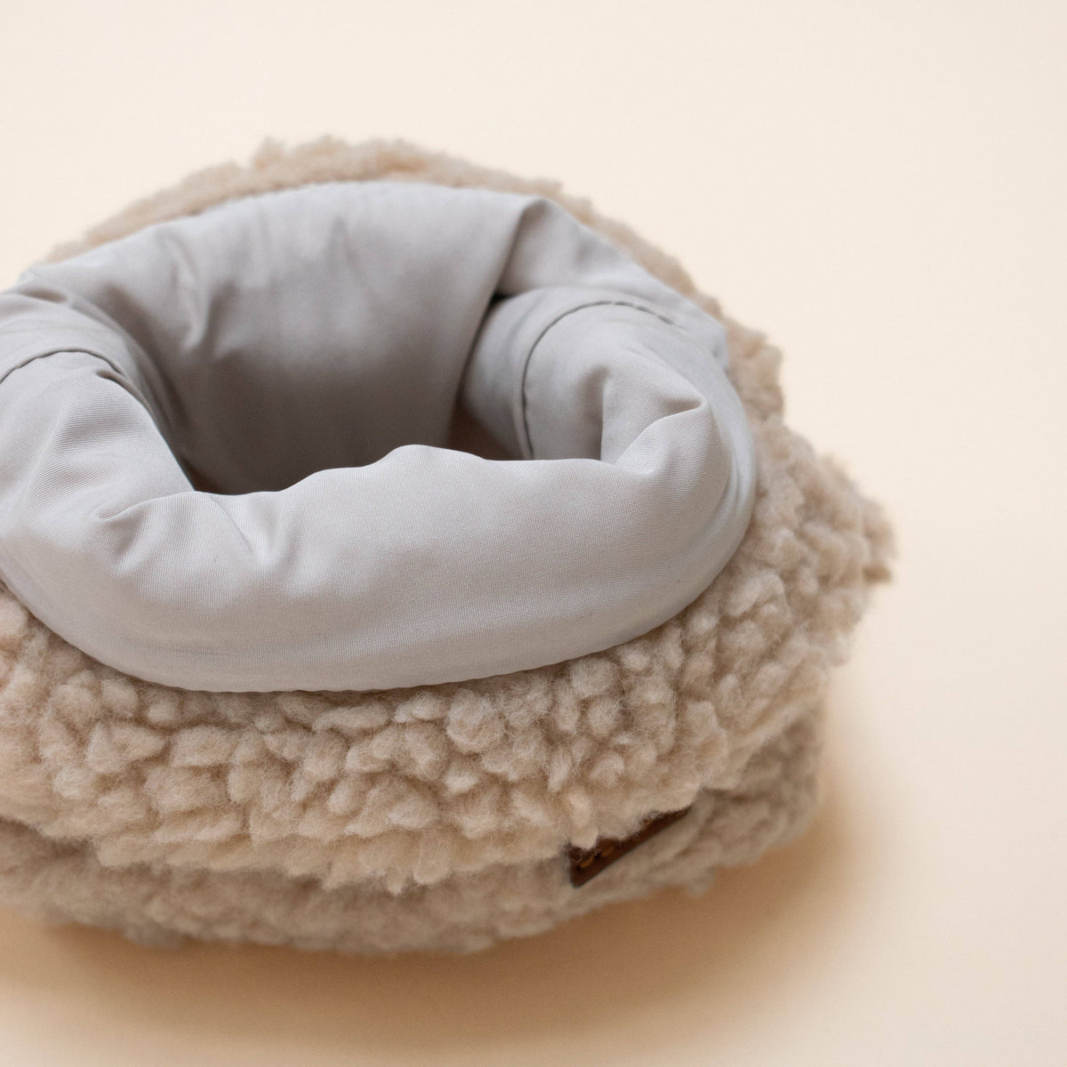 Neck warmer with gray interior and beige fleece exterior on a light background