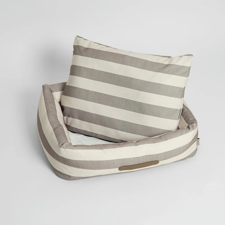 Striped pet bed with a pillow on a light gray background