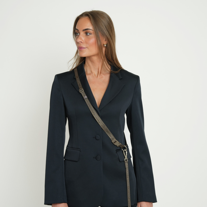 Woman wearing a black blazer with a strap over her shoulder on a white background