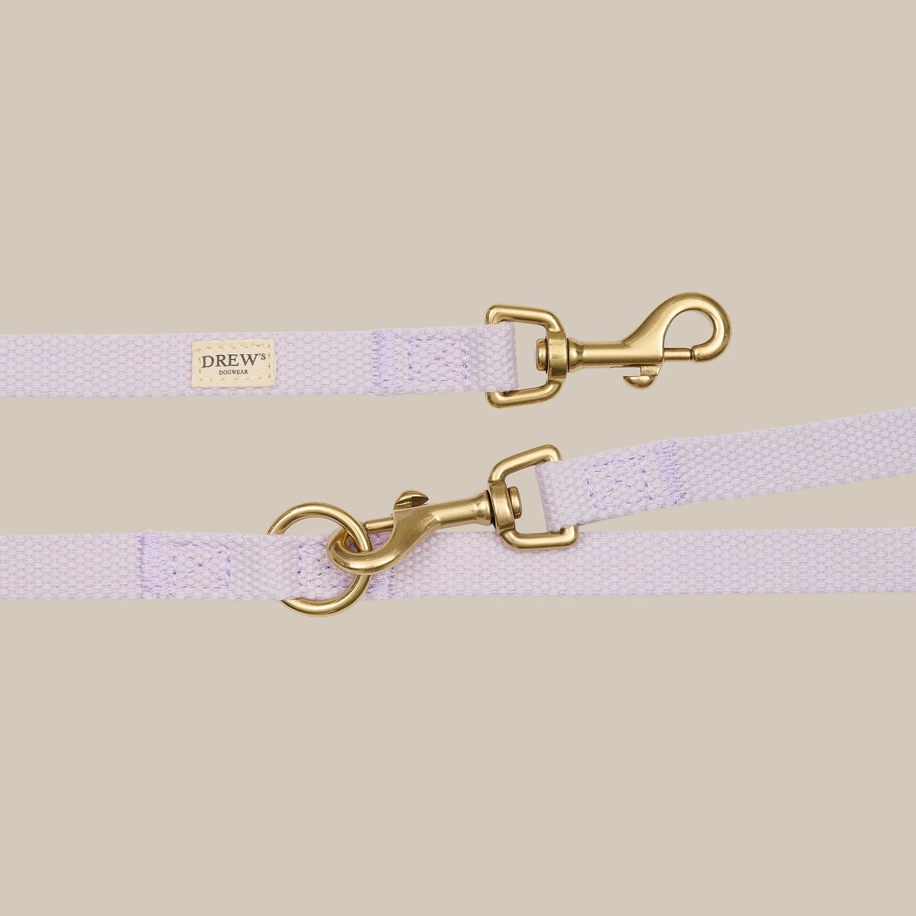 Lavender dog leash with gold hardware on a beige background