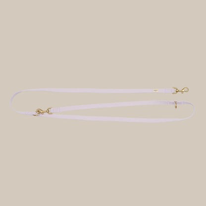 Thin lavender leash with gold hardware on a beige background