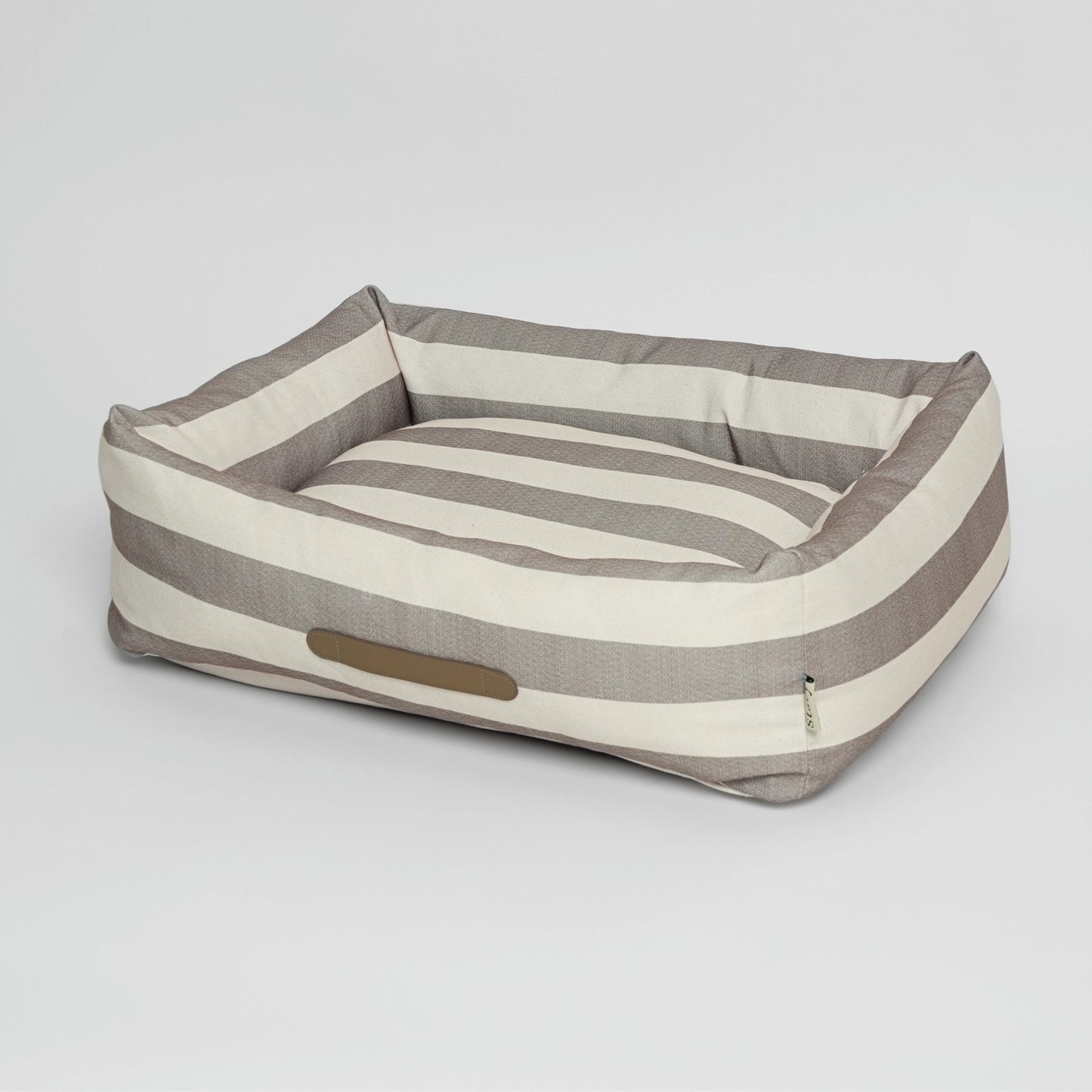 Striped dog bed with a pillow on a light gray background