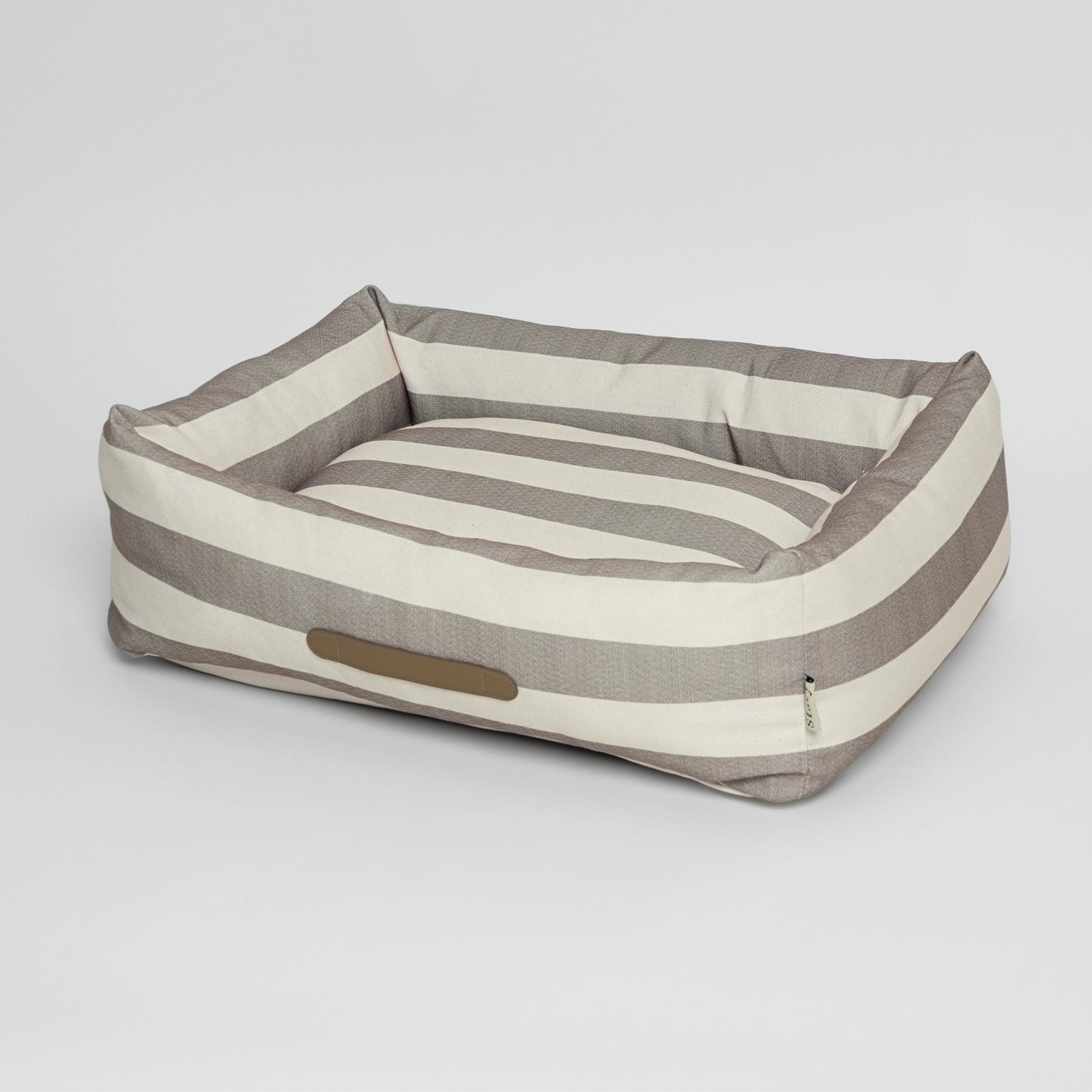 Striped dog bed with a pillow on a light gray background