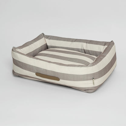 Striped dog bed with a pillow on a light gray background