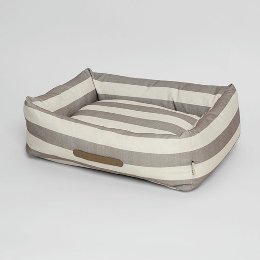 Striped dog bed with a pillow on a light gray background