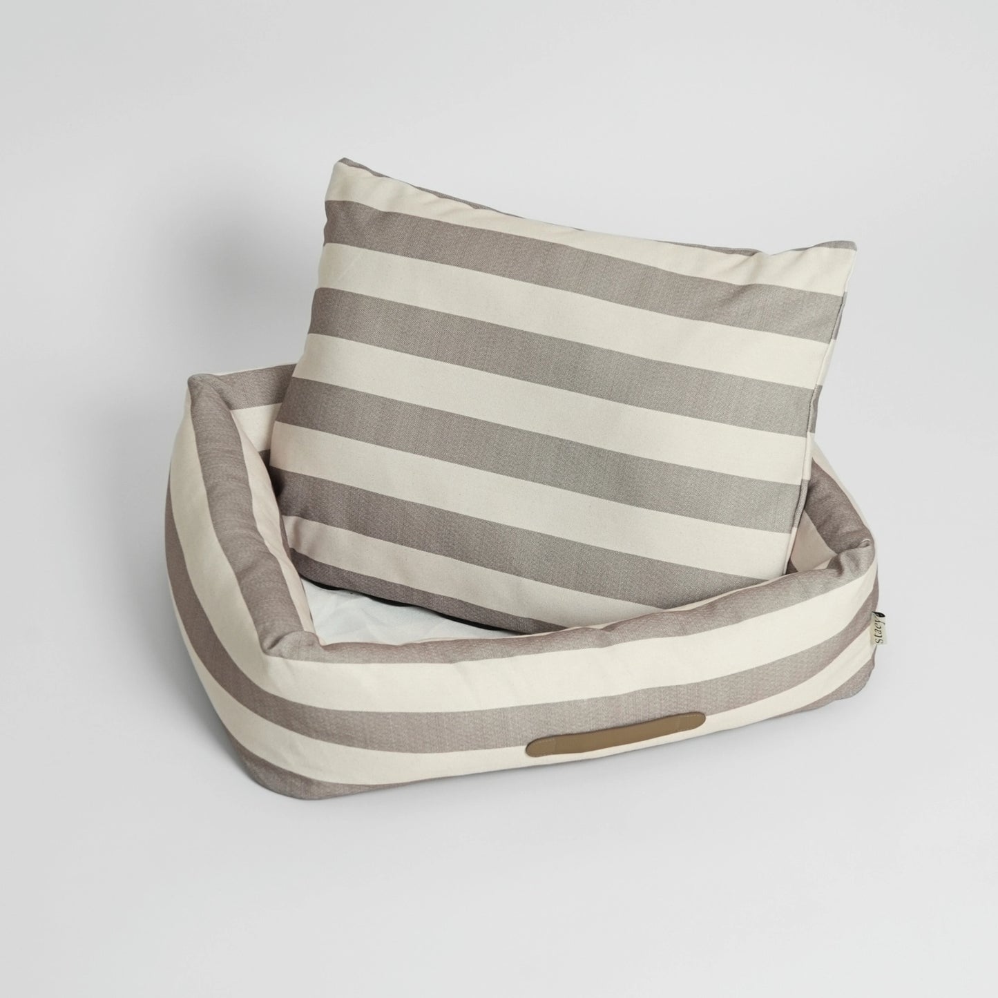 Striped pet bed with a pillow on a light gray background