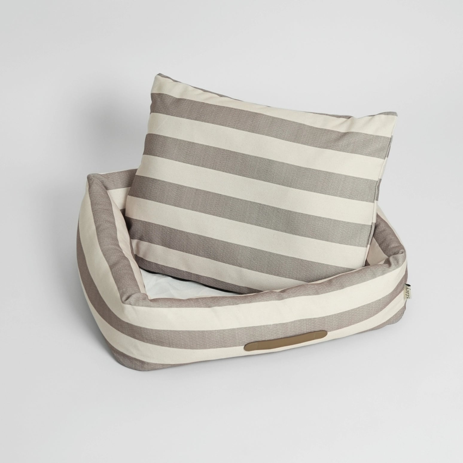 Striped pet bed with a pillow on a light gray background