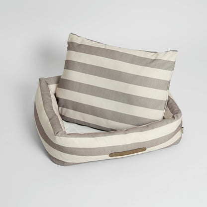 Striped pet bed with a pillow on a light gray background