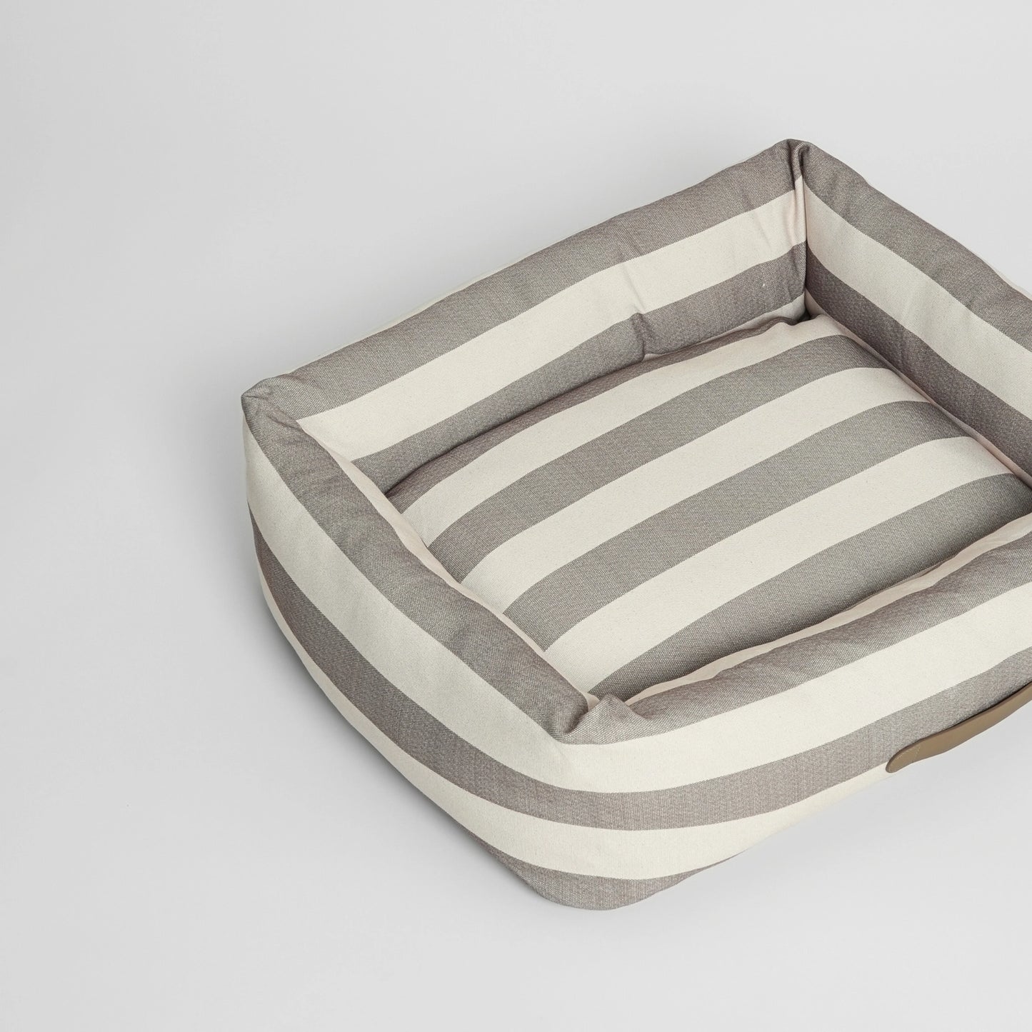 Striped dog bed with a pillow on a light grey background