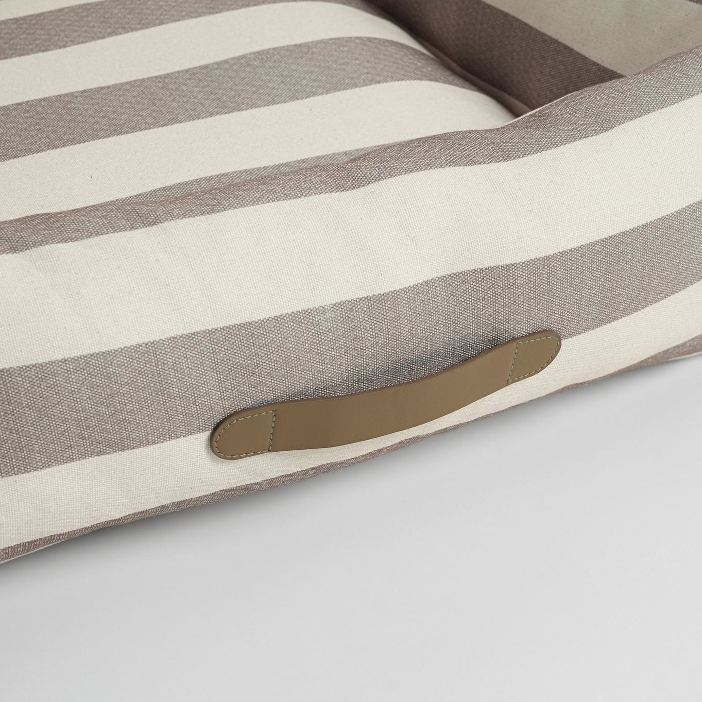 Striped dog cushion with a brown patch on a light gray background