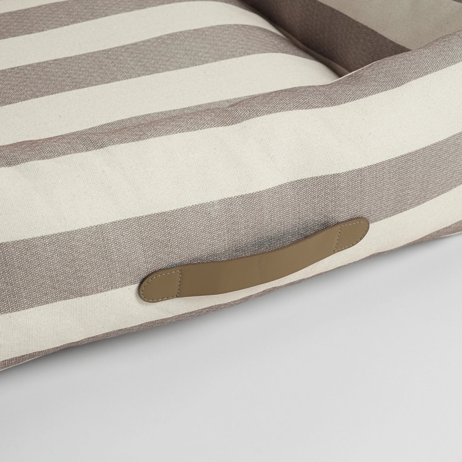 Striped dog cushion with a brown patch on a light gray background