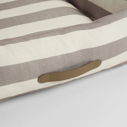 Striped dog cushion with a brown patch on a light gray background