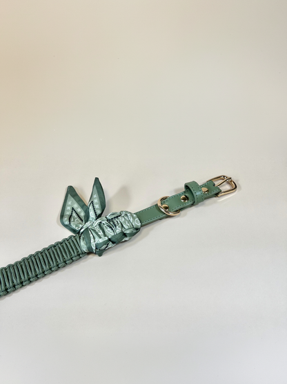 Green leather belt with bow detail on a light gray background