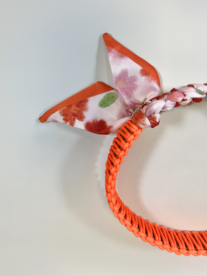 Orange headband with a floral bow on a light gray background