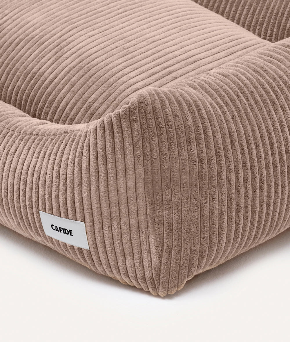 Beige corduroy pet bed with a visible brand label on a white background