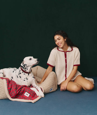 Woman in a white and red outfit sitting next to a Dalmatian dog on a blue floor with a dark green background.