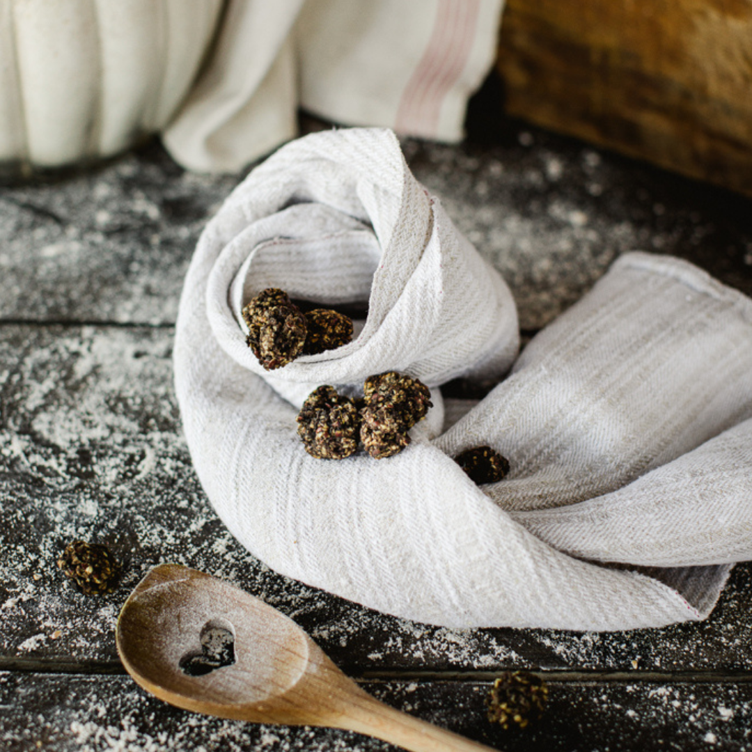 Black truffles on a white cloth with a wooden spoon on a dark surface