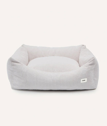 Gray pet bed with a white pillow on a white background
