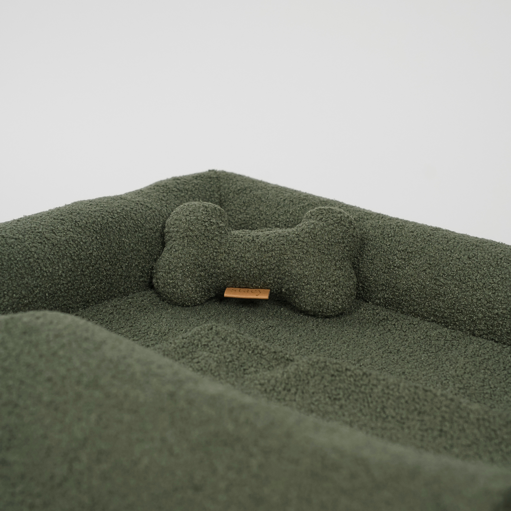 Green pet bed with a bone-shaped pillow on a light gray background