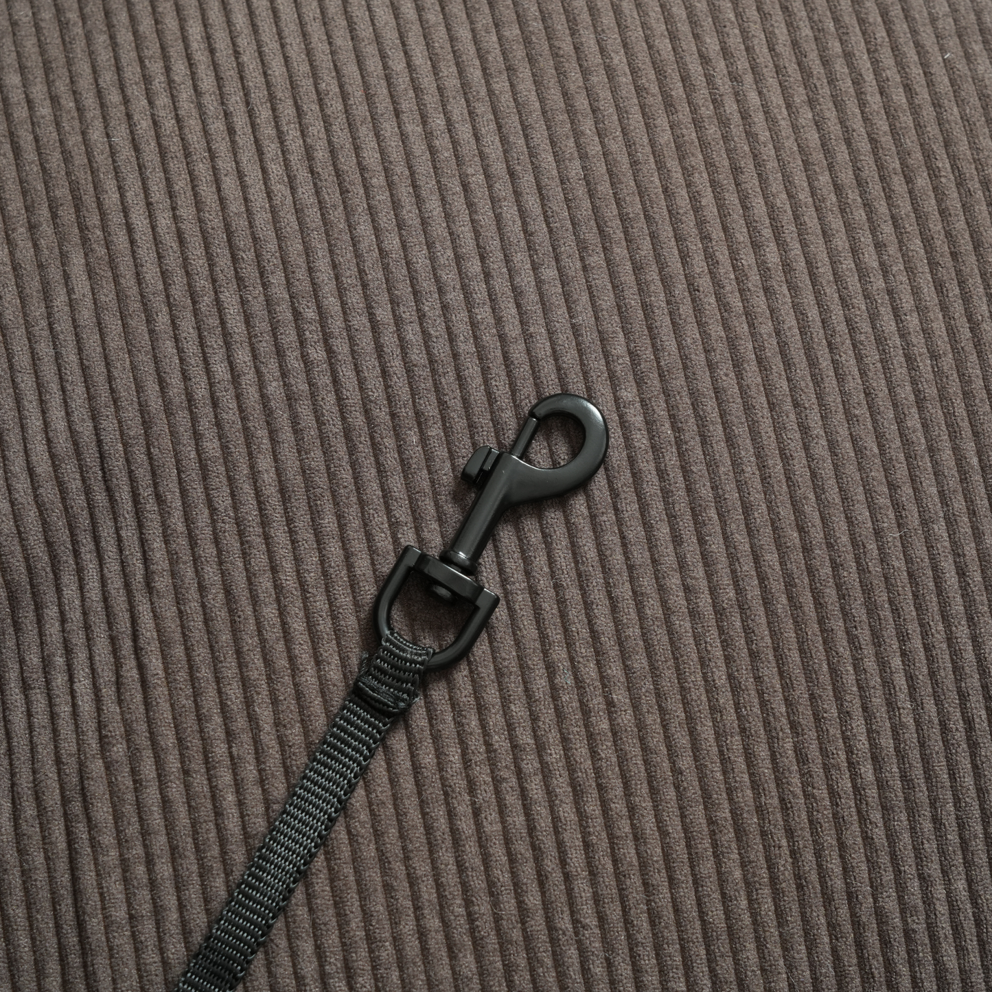 Black strap with a clip on a brown textured background