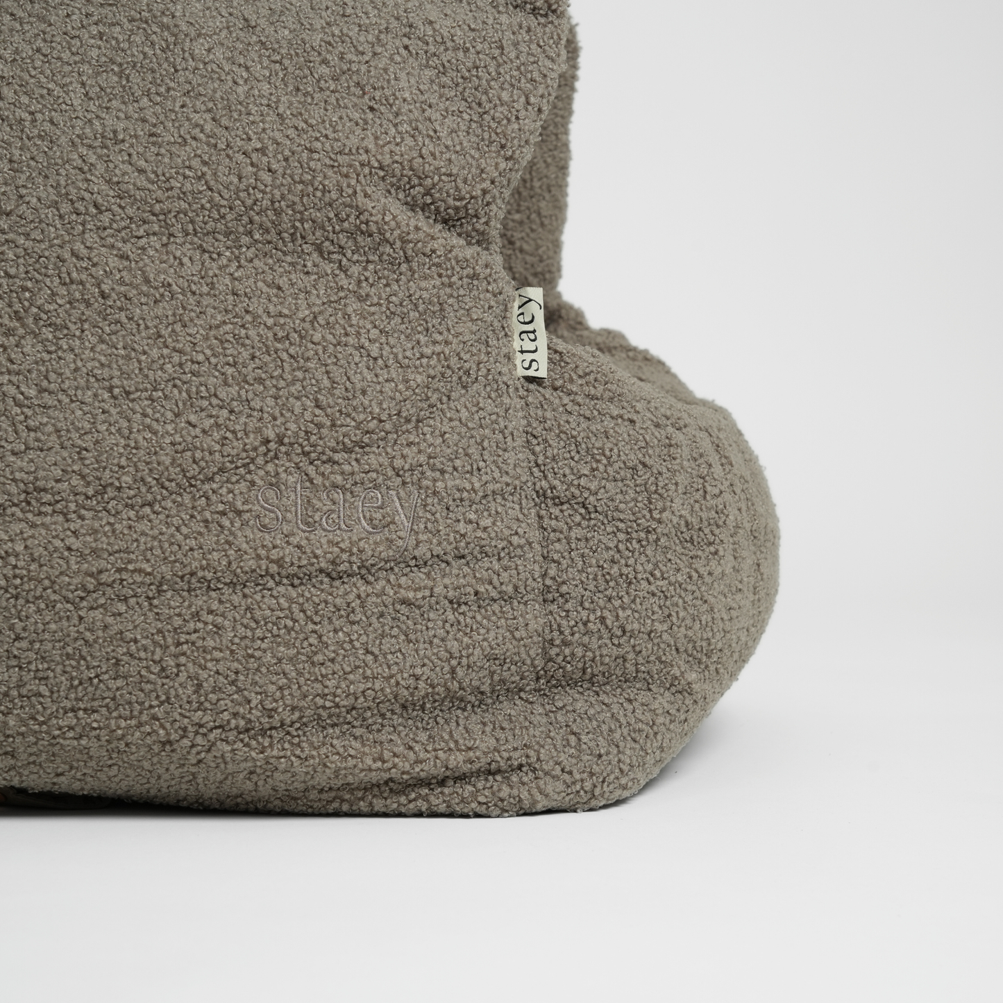 Gray fleece slippers with a brand tag on a light gray background