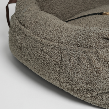 Close-up of a textured brown pet bed on a light gray background