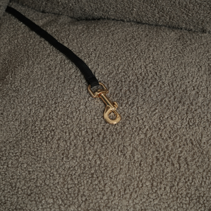 Close-up of a textured fabric surface with a gold clasp on a black cord.