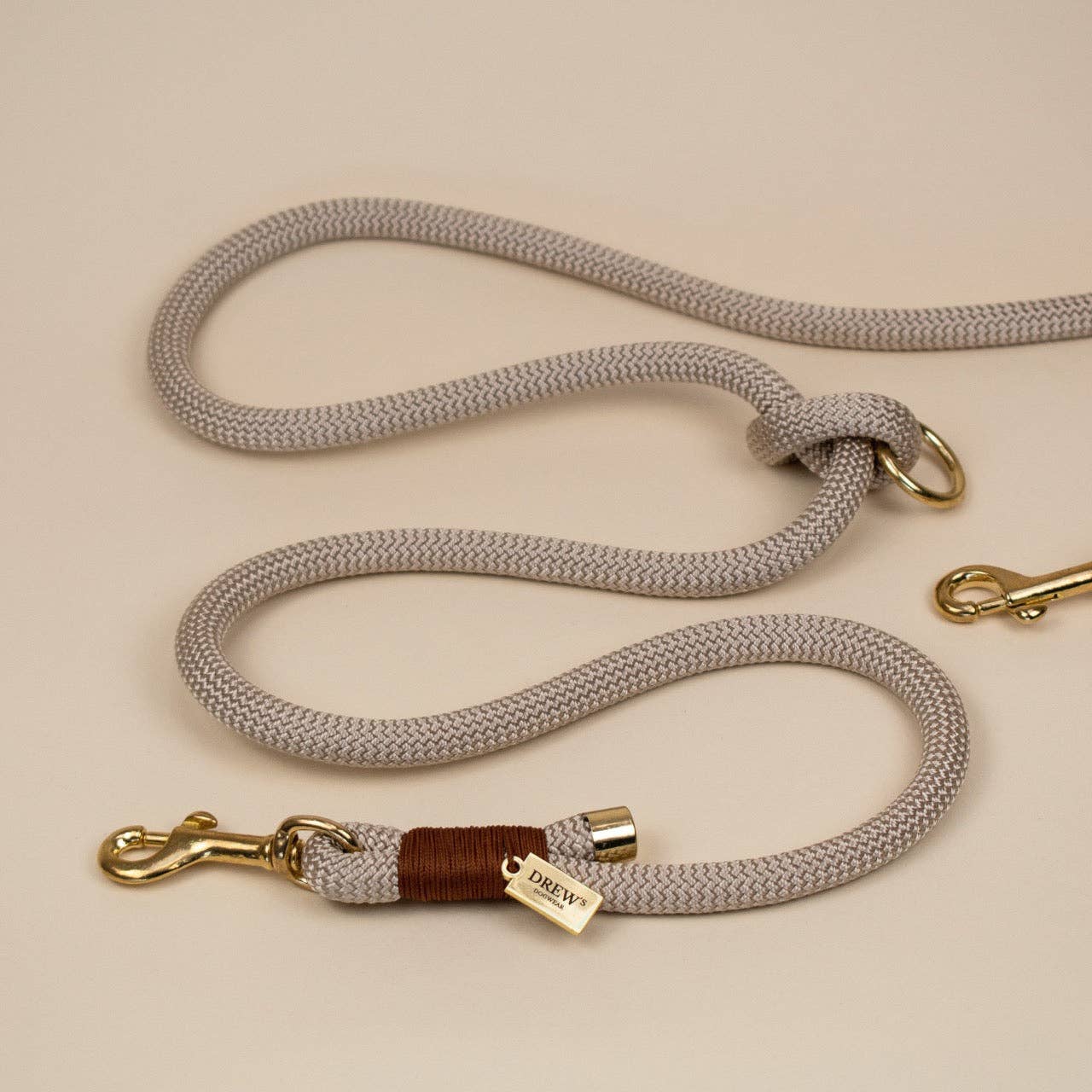 Gray dog leash with gold hardware on a beige background