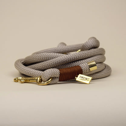 Coiled gray dog leash with gold and brown accents on a beige background