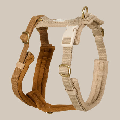 Two dog harnesses, one brown and one beige, on a beige background.