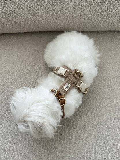 White fluffy dog toy with a brown harness on a gray surface