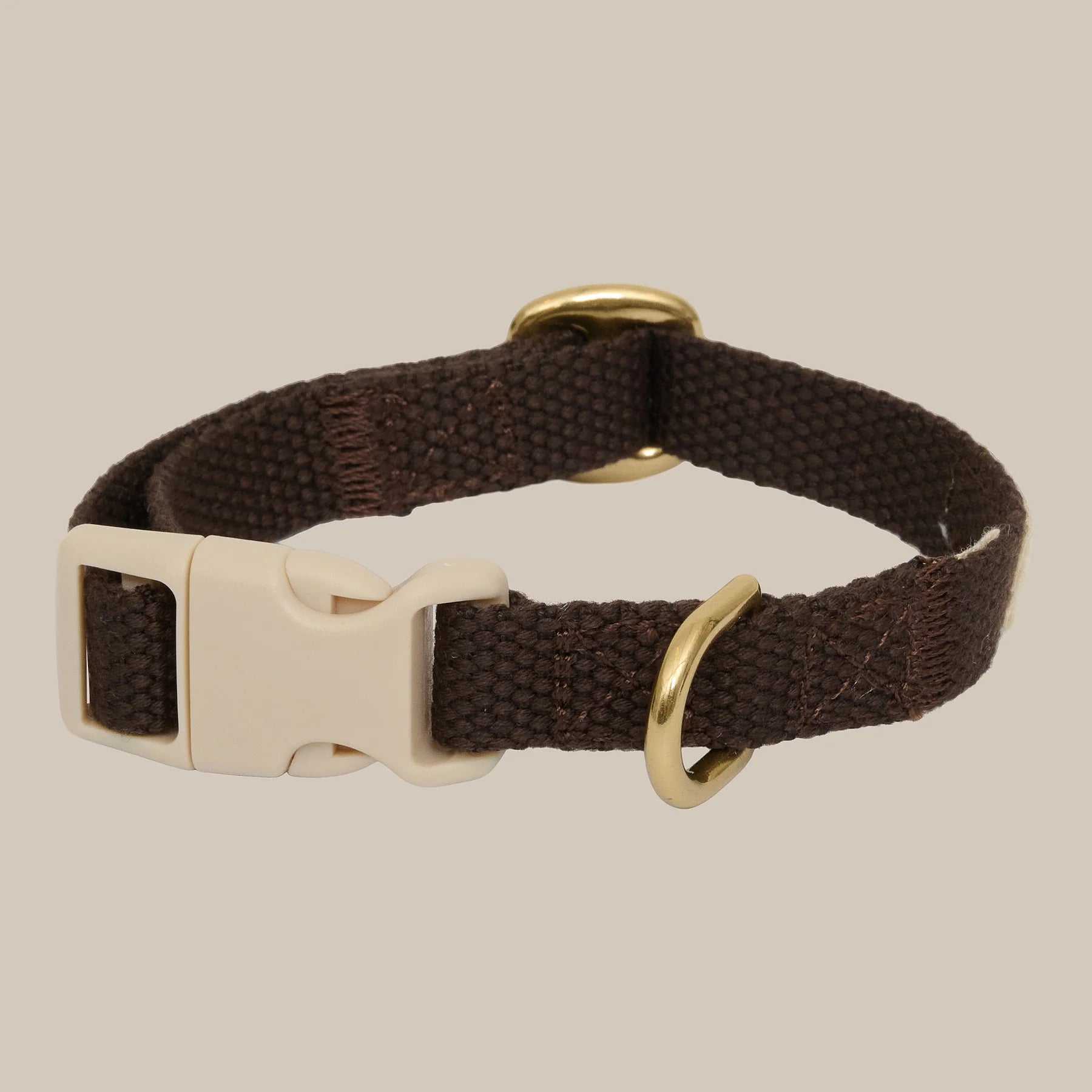Brown dog collar with a beige buckle on a beige background