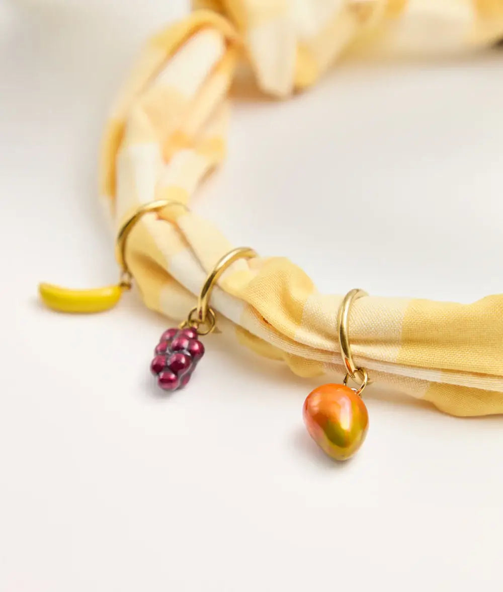 Bracelet with fruit-shaped charms on a yellow fabric background