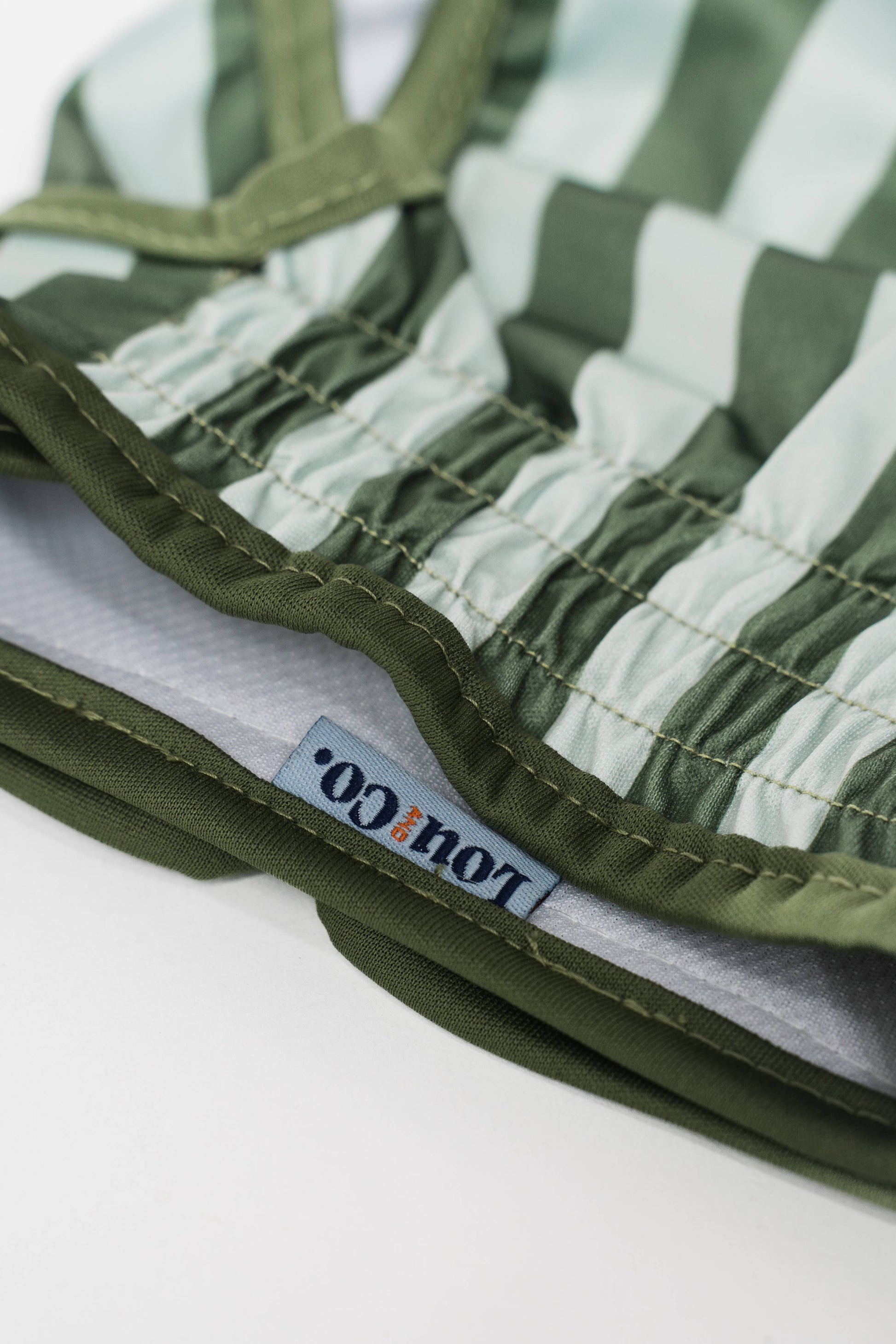 Stack of green and gray striped fabric with a brand label on a white background