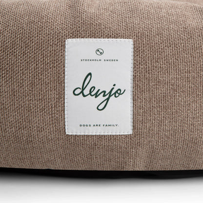 Brown fabric surface with a white label featuring the brand 'denjo'.
